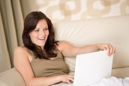 Smiling woman sitting with laptop sofa