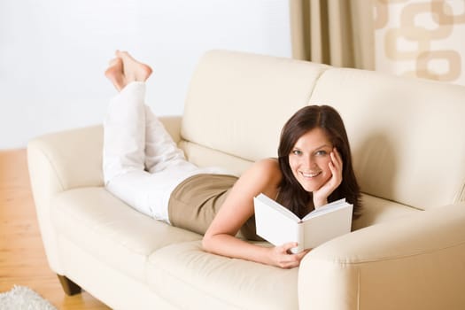 Young happy woman read book on sofa