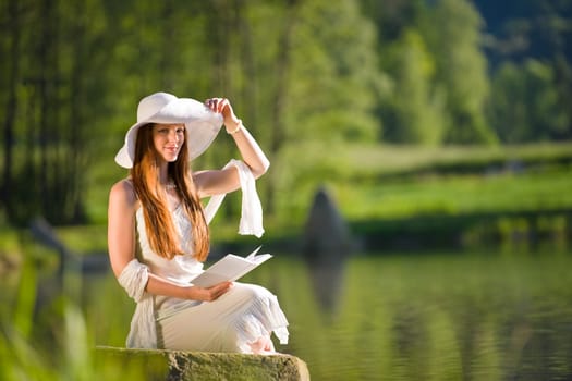Long red hair romantic woman relax by lake with book