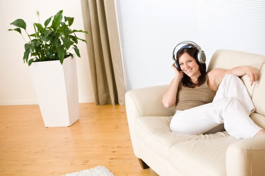 Smiling woman with headphones  listen to music in lounge
