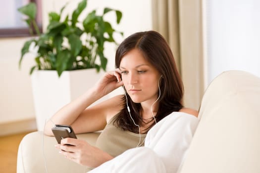 Woman holding music player listening on sofa home