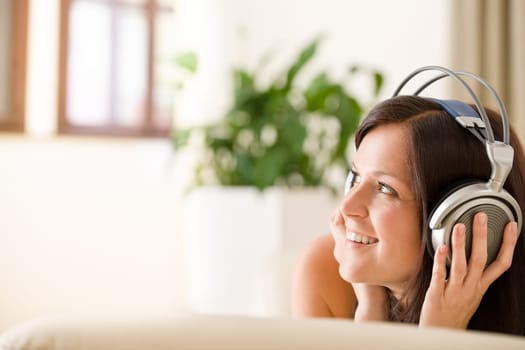Smiling woman with headphones  listen to music in lounge