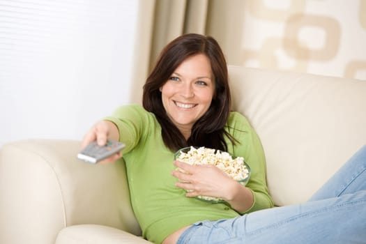 Woman watching television with popcorn in living room