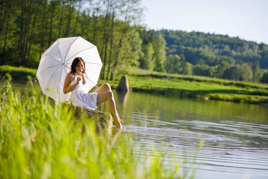 Happy romantic woman sitting by lake