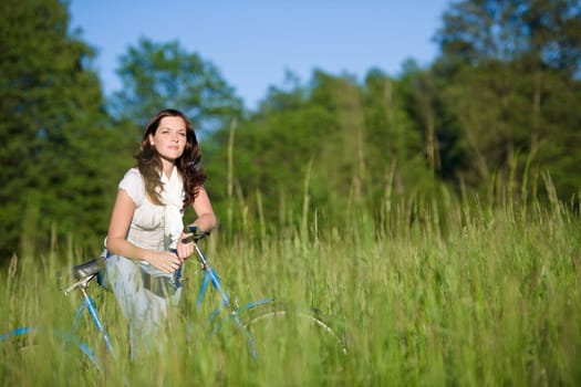 Woman with old-fashioned bike in meadow