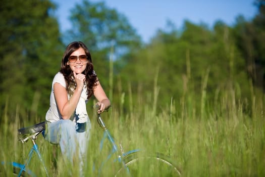 Woman with old-fashioned bike in meadow