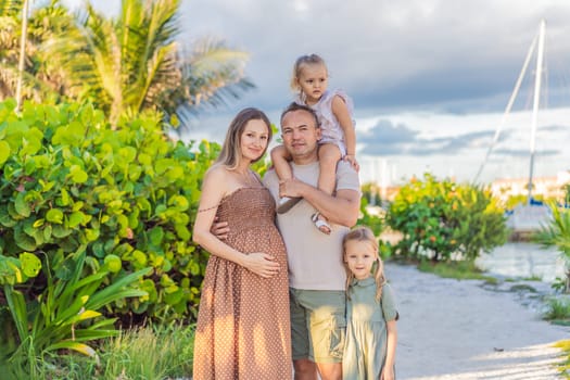 A happy, mature couple over 40 with their two daughters, enjoying a leisurely walk in a park, their joy evident as they embrace the journey of pregnancy later in life.