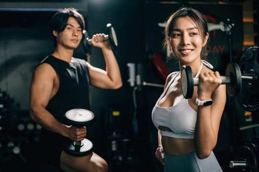 Portrait young fit man and woman, in black workout clothes and holding dumbbells, stand together with a cheerful attitude, ready for their exercise routine. lifestyle fitness concept