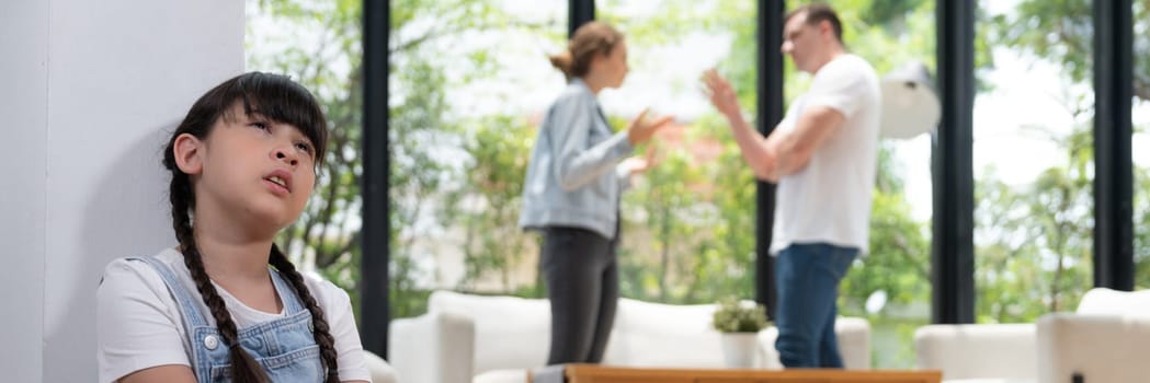 Stressed and unhappy young girl huddle in corner crying and sad while her parent arguing in background. Domestic violence at home and traumatic childhood develop to depression. Panorama Synchronos