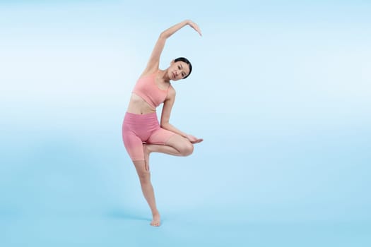 Asian woman in sportswear doing yoga exercise in standing pose on fitness as her workout training routine. Healthy body care and meditation yoga lifestyle in full shot on isolated background. Vigorous