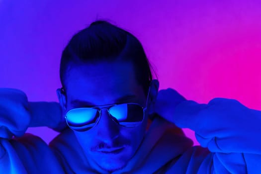 Portrait of a millennial man in neon light. Hipster in a hoodie. Selective focus