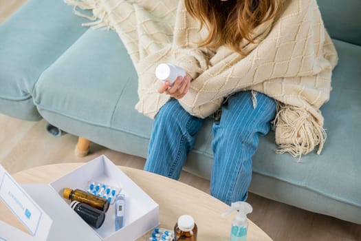 Asian young woman reading ingredient and hold bottle of drug on sofa at home, sick people reading information medicine label pills, female with flu virus, Health care and medicine concept