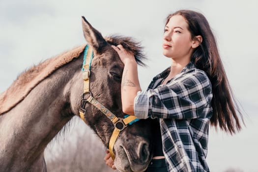 Cute happy young woman with horse. Rider female drives her horse in nature on evening sunset light background. Concept of outdoor riding, sports and recreation.