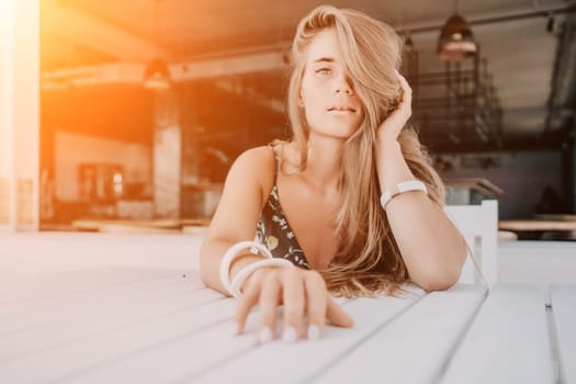 Happy woman portrait in cafe. Boho chic fashion style. Outdoor photo of young happy woman with long hair, sunny weather outdoors sitting in modern cafe