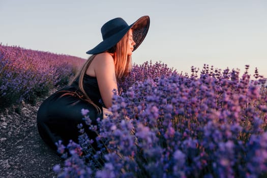 Close up portrait of young beautiful woman in a white dress and a hat is walking in the lavender field and smelling lavender bouquet.