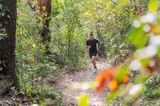 man practicing trail running in the forest, concept of sport in nature and healthy lifestyle, copy space for text