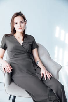 a woman in black dress sits in a chair in a bright room