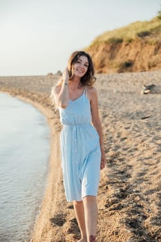 woman in a sundress walks along the seashore on the beach walk
