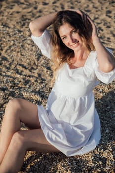 a woman sitting on small pebbles on the beach rest walk