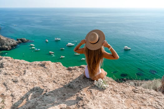 Woman travel sea. Happy woman in a beautiful location poses on a cliff high above the sea, with emerald waters and yachts in the background, while sharing her travel experiences.