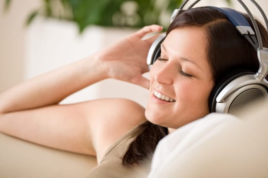 Smiling woman with headphones  listen to music in lounge