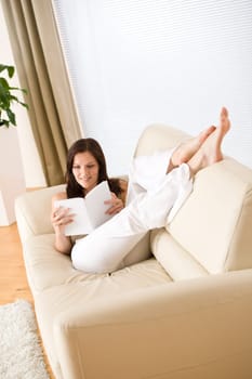 Young happy woman read book on sofa