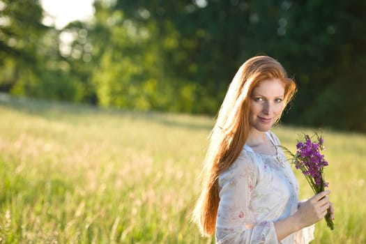 Long red hair woman in romantic sunset meadow