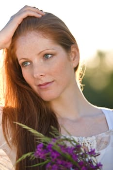 Long red hair woman in romantic sunset meadow