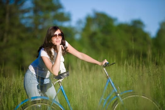 Woman with old-fashioned bike in meadow