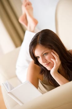 Young happy woman read book on sofa