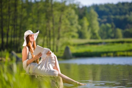 Long red hair romantic woman relax by lake with book