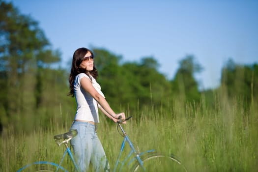 Woman with old-fashioned bike in meadow