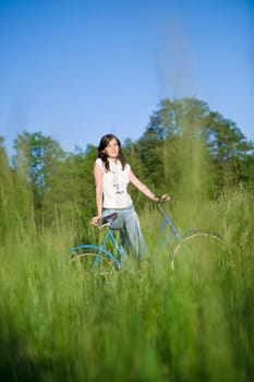 Woman with old-fashioned bike in meadow