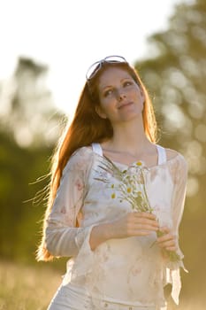 Long red hair woman in romantic sunset meadow