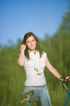 Woman with old-fashioned bike in meadow