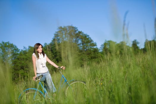 Woman with old-fashioned bike in meadow