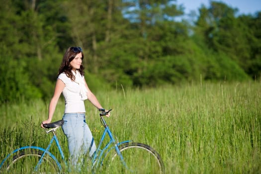 Woman with old-fashioned bike in meadow