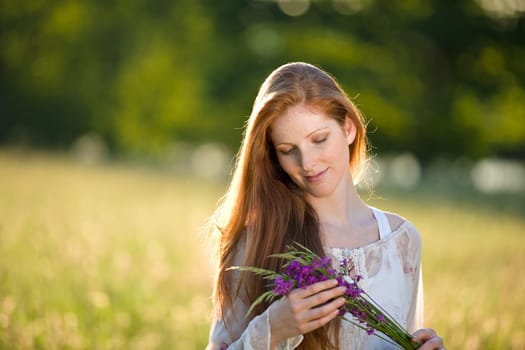Long red hair woman in romantic sunset meadow