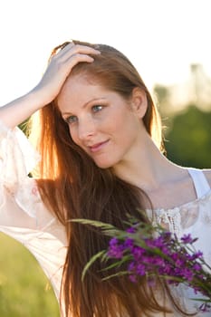 Long red hair woman in romantic sunset meadow