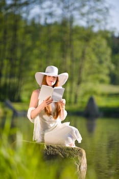 Long red hair romantic woman relax by lake with book