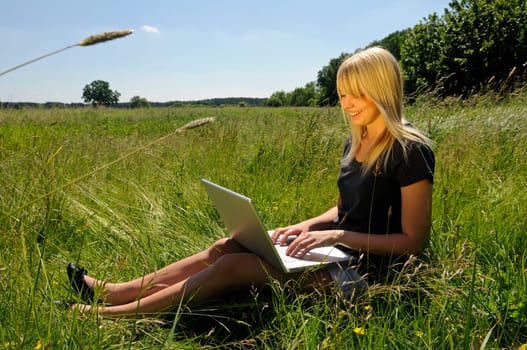 Young woman using laptop on a meadow