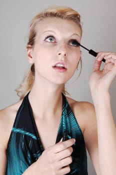 Blond girl fixing her eyelashes.