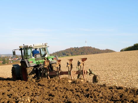 Tractor ploughs brown field