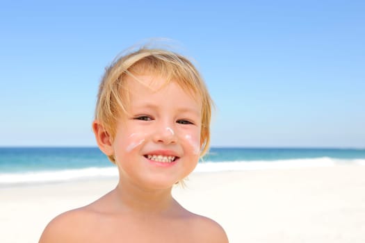 Kid with sunscreen on face on the beach