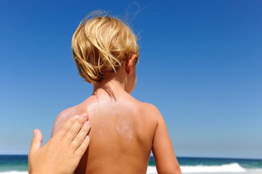 Mother applying sunscreen to child on the beach
