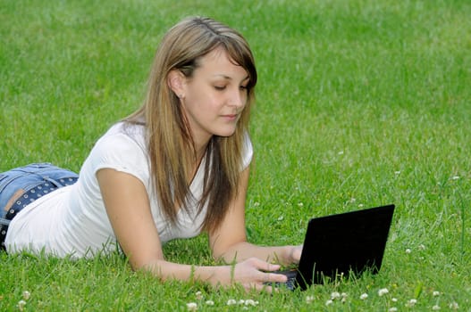 Young woman with netbook on meadow