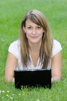 Young woman with netbook on meadow