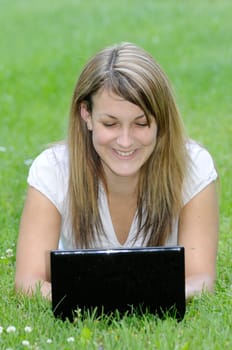 Young woman with netbook on meadow