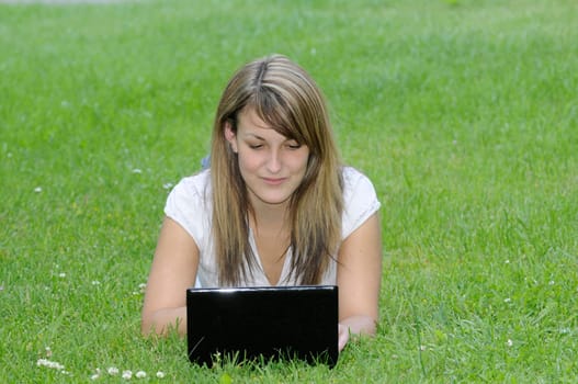 Young woman with netbook on meadow
