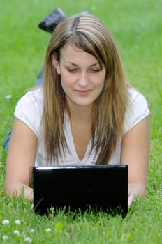 Young woman with netbook on meadow